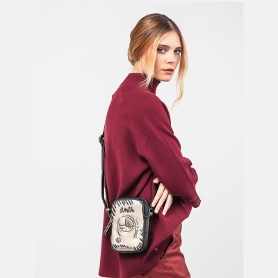 Mulher com camisola bordô e mochila pequena cinza e preta com ilustração e texto