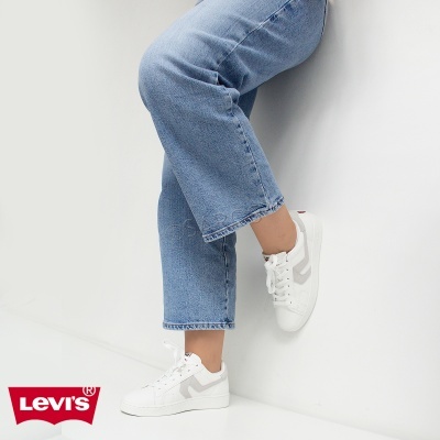 Ténis brancos com detalhes cinza claros usados com jeans azuis