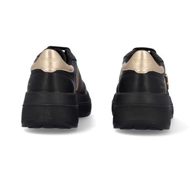 Ténis pretos com detalhes dourados e sola grossa vistos de trás