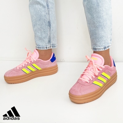 Ténis Adidas rosa com riscas amarelas e verdes usados com jeans claros