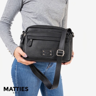 Mala de pele preta com tira ajustável e pessoa segurando