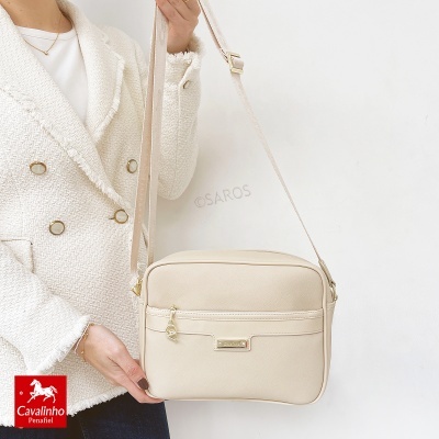 Mala tiracolo bege com etiqueta Cavalinho e casaco branco texturado com botões dourados.