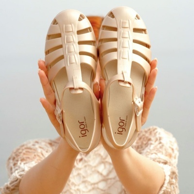 Sandálias bege de gel Igor seguradas por uma pessoa.