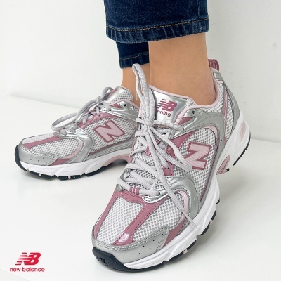 Ténis New Balance brancos, prata e rosa em pés com jeans