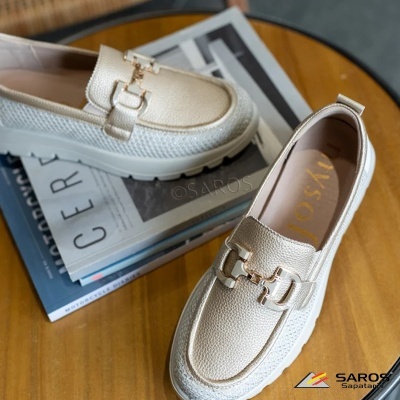 Par de sapatos tipo mocassim bege claro com aplicação metálica dourada sobre mesa de madeira