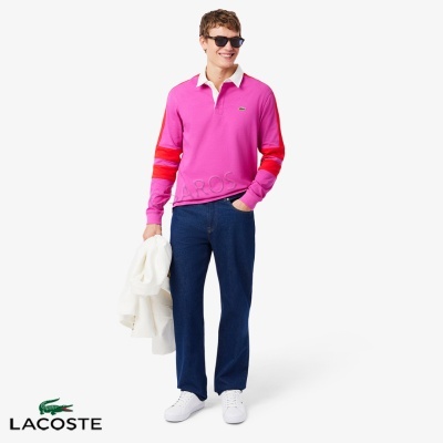 Homem com camisola polo rosa e calças azuis em fundo branco