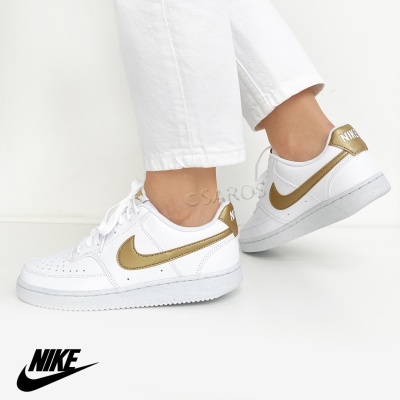 Ténis brancos Nike com detalhes dourados e logo visível