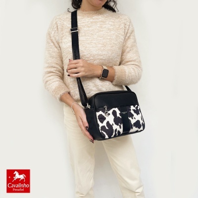 Mala de ombro Cavalinho preta com padrão animal print e pessoa com camisola bege felpuda e calças claras