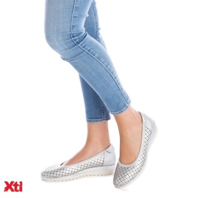 Sapatilhas prateadas perfuradas com sola branca, usadas com calças de ganga