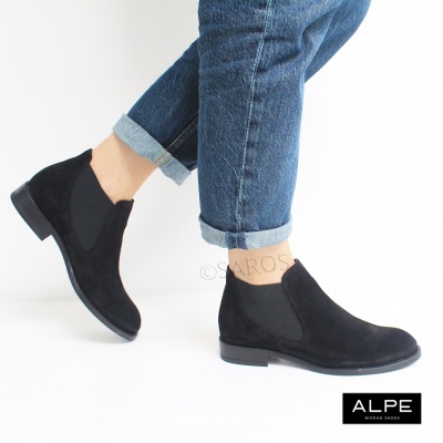 Botins pretos em camurça com elásticos laterais e sola preta, usados com calças jeans azuis