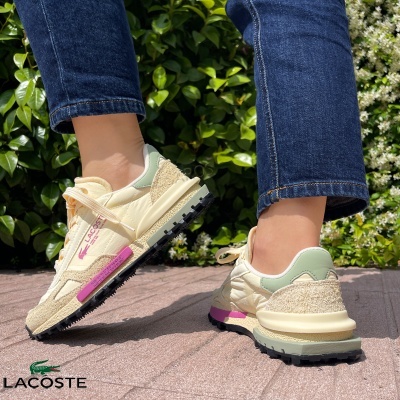 Ténis Lacoste creme e rosa com sola preta usados com calças de ganga azuis
