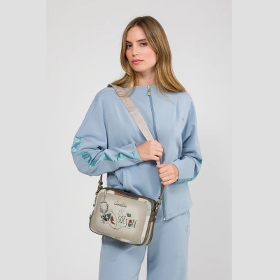 Mulher com fato de treino azul claro e mala bege com texto LIFE GOES ON