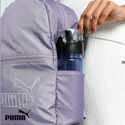 Mochila lilás PUMA com garrafa azul no bolso lateral ao lado de pessoa com camisola branca