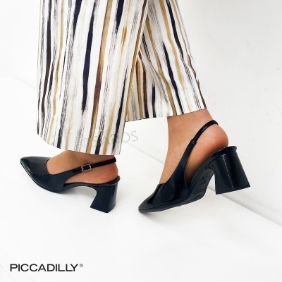Sapatos pretos de salto médio com tiras no calcanhar e calças às riscas.