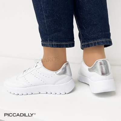 Ténis brancos com detalhe prateado na parte atrás e calças de ganga escuras.