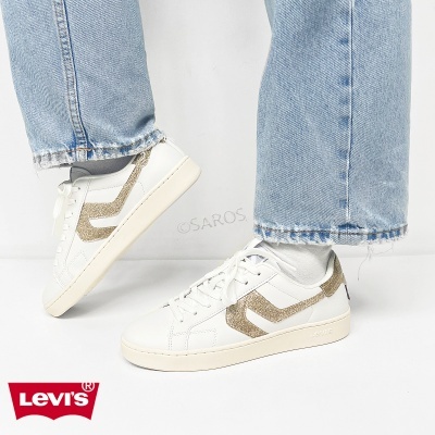 Ténis Levis brancos com risca dourada brilhante usados com jeans azul claro e meias brancas