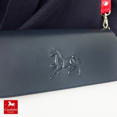 Mala de pele azul escura com relevo de cavalo e alça vermelha
