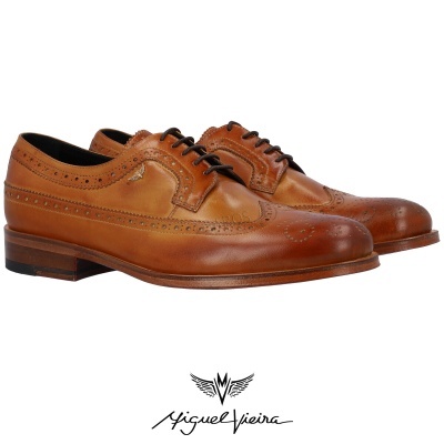Sapatos de pele castanha com padrão brogue e atacadores pretos.