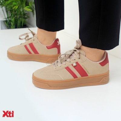 Ténis bege com riscas vermelhas e sola caramelo.