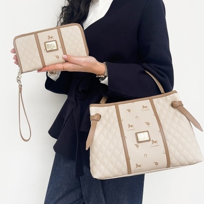 Mala e carteira bege com padrão Cavalinho e ferragens douradas segurados por mulher.