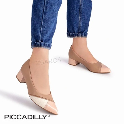 Sapatos de senhora bege com salto baixo e biqueira verniz usados com jeans azuis.