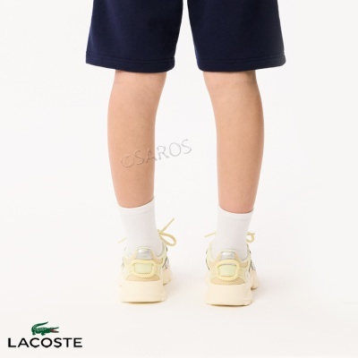 Pernas de criança com calçado desportivo branco e meias brancas, calções azuis escuros