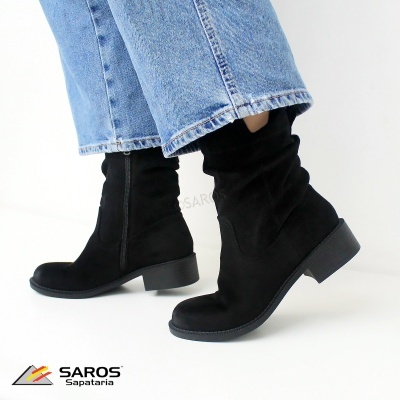 Botas pretas de camurça com fecho lateral e calças de ganga azuis.