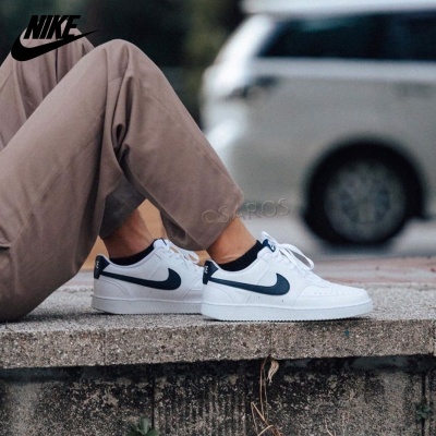 Ténis Nike brancos com detalhes em azul escuro usados ao ar livre