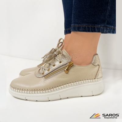 Tênis bege com detalhes metálicos dourados e atacadores com riscas douradas