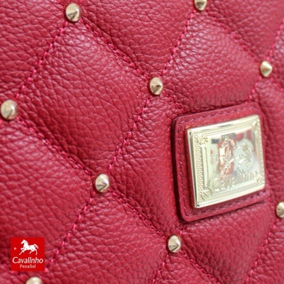 Bolsa vermelha em pele matelassê com tachas e placa metálica dourada