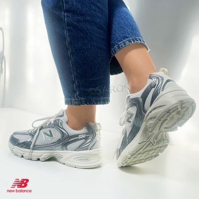 Sapatilhas New Balance 530 branco e prateado com jeans azuis