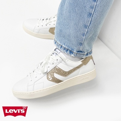 Ténis Levis brancos e dourados usados com jeans azuis claros