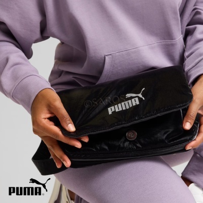 Bolsa preta Puma com fecho sendo segurada por pessoa com roupa lilás