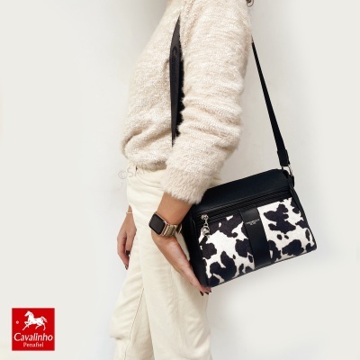 Mala tiracolo preta e branca com padrão de manchas e detalhe em couro