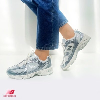 ténis New Balance femininos branco e prateado com jeans azuis