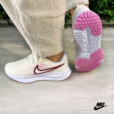 Ténis ténis Nike branco com detalhes rosa e bordô usados por pessoa com calças claras