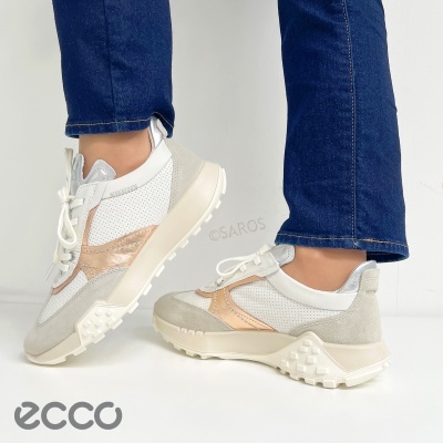 Tênis casual bege, branco e cobre metálico com sola antiderrapante usados em piso branco