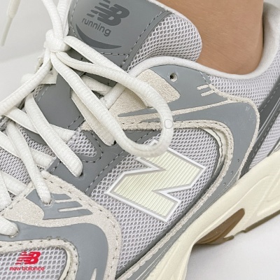 Ténis New Balance cinzento, branco e bege com logo 'NB running' e 'N'