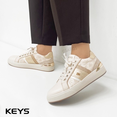 Sapatilhas creme e dourado com padrão e brilho, usadas com calças pretas