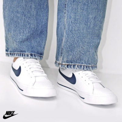 Ténis brancos Nike com swoosh preto e calças de ganga azuis