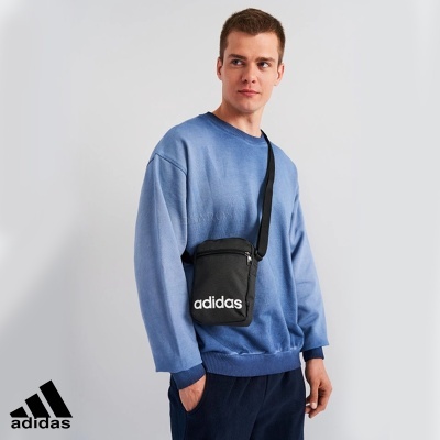Homem com bolsa preta Adidas e camisola azul