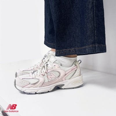 Ténis New Balance 530 branco com detalhes cor de rosa e cinza usados com calças de ganga e meias brancas