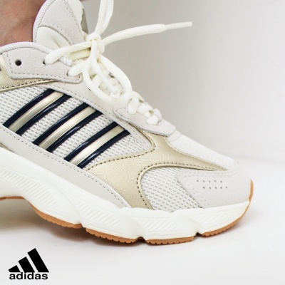 Tênis branco Adidas com detalhes pretos e bege em fundo branco