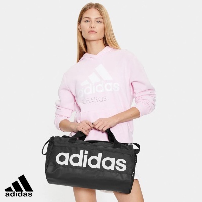 Mulher com camisola rosa e mala preta adidas