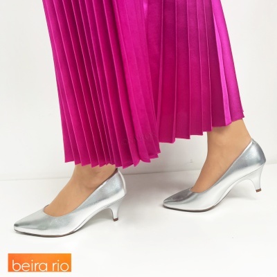 Sapatos prateados de salto médio com saia rosa plissada.