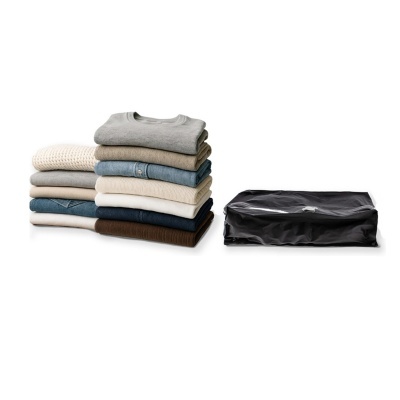 Pilha de roupas dobradas em tons neutros e azuis com saco preto ao lado