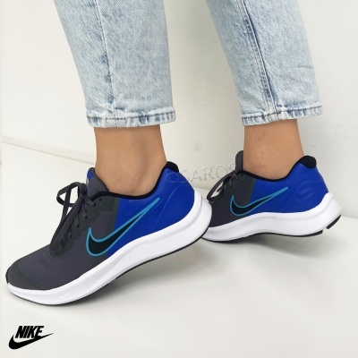 Sapatilhas Nike pretas e azuis com sola branca usadas com jeans claros