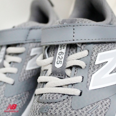 Ténis desportivos cinzentos New Balance com cadarços brancos e etiqueta 625