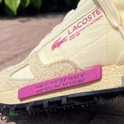 Ténis Lacoste bege com detalhes em rosa e texto com coordenadas