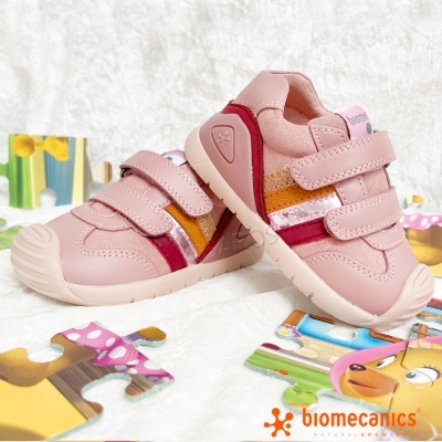 Ténis infantis rosa com tiras de velcro e detalhes coloridos em superfície branca com puzzle